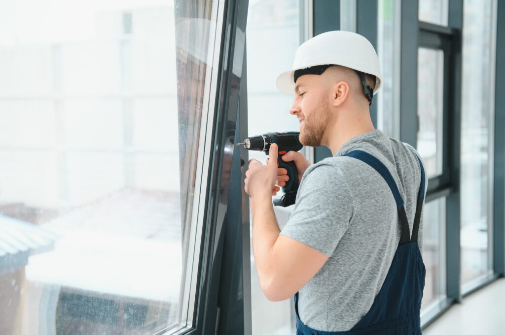 handsome young man installing bay window in new house construction site